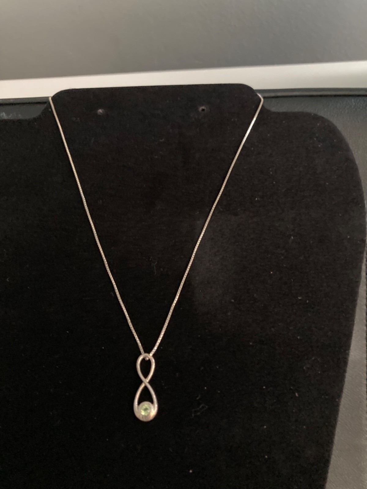 A silver 925 infinite knot pendant set with a peridot with silver box chain